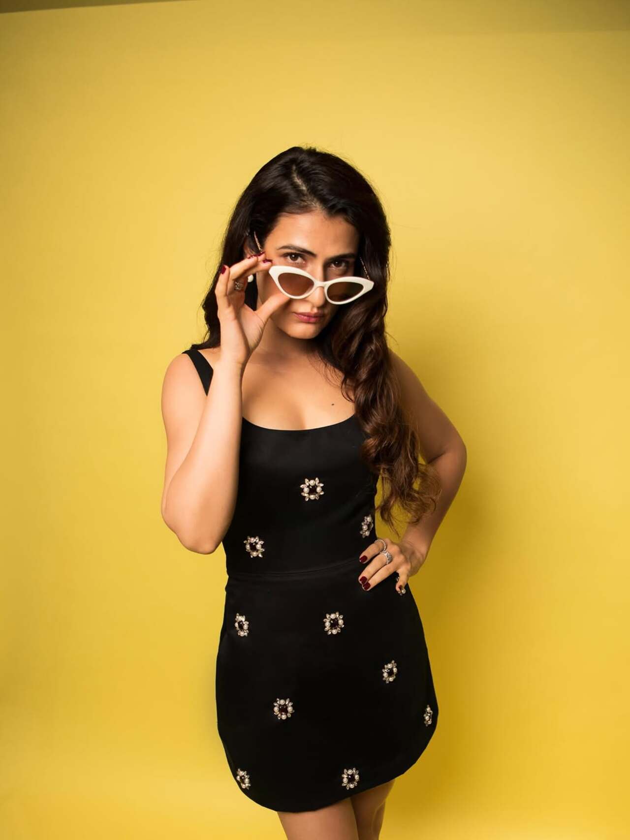 Fatima adds retro flair with pearl-embellished flowers on a black mini, topped off with white cat-eye sunglasses—playful, confident, and very Metro